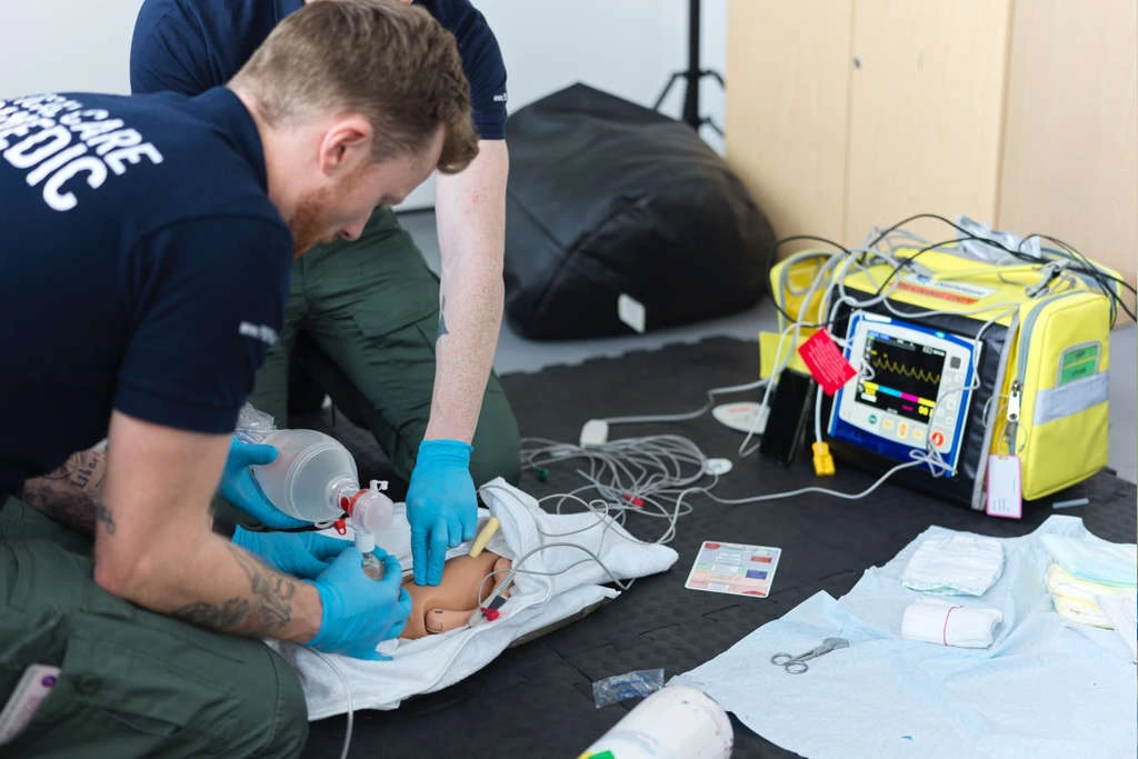 Two paramedics training emergency new-born life support on a mannequin